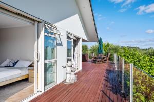a balcony of a house with a bed and umbrella at RidgeRaj - Kerikeri Holiday Home in Kerikeri