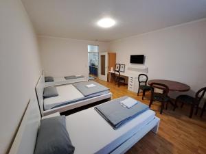 a room with two beds and a desk and a table at Apart Sudenburg / Magdeburg in Magdeburg