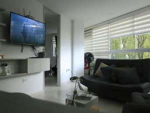 uma sala de estar com um sofá preto e uma televisão de ecrã plano em Apartamento nuevo, próximo al metro y CC Mayorca em Sabaneta