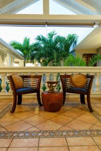 two benches sitting on a patio with palm trees at Villa Kapresse du 978 - Guest house in Saint Martin