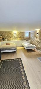 a bedroom with two beds and a stone wall at La maison du bonheur in Caumont-sur-Durance