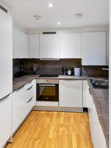 a kitchen with white cabinets and a wooden floor at Luxury 1 bedroom Apartment in London overseeing Canary Wharf with free parking in London