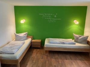 two beds in a room with a green wall at Ferienwohnung Morgensonne in Bad Berka