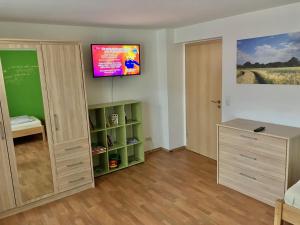 Habitación con TV en la pared y estante para libros. en Ferienwohnung Morgensonne, en Bad Berka