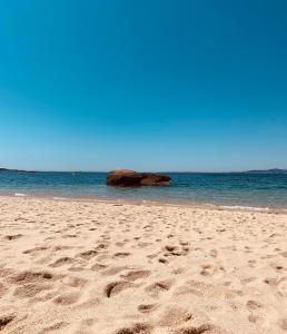 a beach with footprints in the sand and the ocean at Apartamento Mar do Grove in O Grove