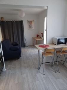 a living room with a table and a microwave at Studio neuf confortable à 10 min à pied de la gare in Nîmes