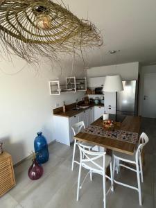 eine Küche mit einem Holztisch und weißen Stühlen in der Unterkunft Le Galatee -T2 luxe les pieds dans l'eau - Porticcio in Porticcio