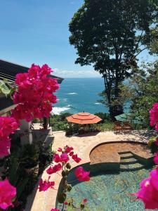 a view of the ocean from a patio with pink flowers at Monkey House in Dominicalito