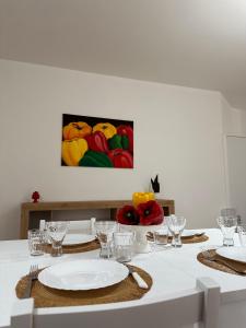 einen Tisch mit Tellern und Gläsern und ein Gemälde an der Wand in der Unterkunft Casa Andrew in Terrasini