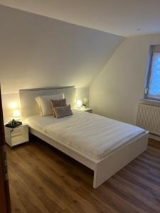 Ferienwohnung Eislingen في آيسلينغن: غرفة نوم بسرير ابيض كبير مع مواقف ليلتين
