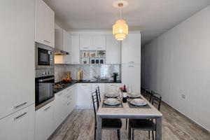 una cocina con armarios blancos y una mesa con sillas. en Bright 2 Bedroom 2 Bath Apartment close to sea en St Paul's Bay