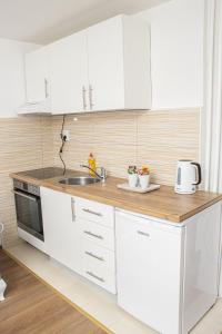 - une cuisine avec des placards blancs et un évier dans l'établissement Apartment Forever, à Tuzla
