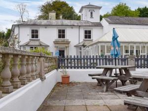 a white house with a wooden fence and a picnic table at 24 Valley Lodge Holiday Cottage in Callington