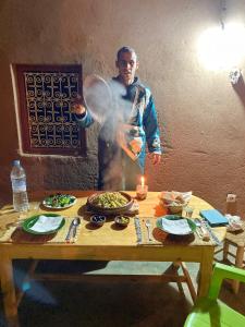 a man is standing in front of a table with food at Casa Familia in Zagora