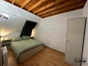 ein Schlafzimmer mit einem Bett und einer Ziegelwand in der Unterkunft La Grange in Carentan