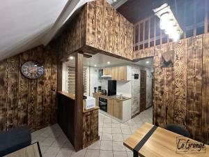 eine Küche mit Holzwänden, einem Tisch und einer Uhr in der Unterkunft La Grange in Carentan
