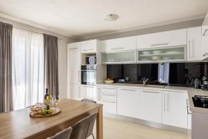 una cucina con armadi bianchi e tavolo in legno di Apartment Under the Rock a Spalato (Split)