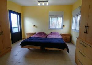Un dormitorio con una cama con sábanas y ventanas púrpuras. en Kosher 'Villa Rosa' Moshav Aderet, Ella Valley nr Bet Shemesh en Adderet