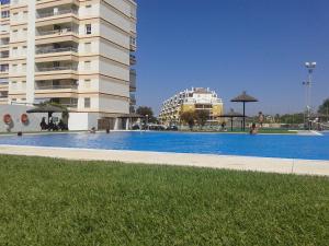 una gran piscina frente a un edificio en Apartamento primera linea de playa Valdelagrana, en El Puerto de Santa María