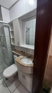 a bathroom with a toilet and a sink and a mirror at Ap. Confortável e funcional. in Brasilia