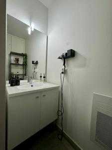 een badkamer met een wastafel, een spiegel en een camera bij Résidence Les Jardins d'Eugénie Near Disneyland in Ferrières-en-Brie