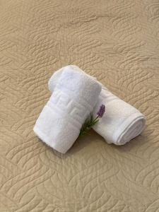 a white towel on a bed with a flower on it at ARTEMIS beach studios in Kalamaki