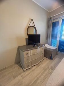 1 dormitorio con tocador con espejo y TV. en Les Sables Noirs & Spa- appartamento multiproprietà, en Vulcano
