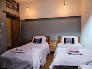 a bedroom with two beds with white blankets at Rose Cottage - Cosy cottage in Millers Dale in Buxton