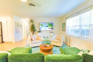uma sala de estar com sofás verdes e uma mesa em Magnolia Home • Clearwater Beach • BBQ • Sunroom em Clearwater