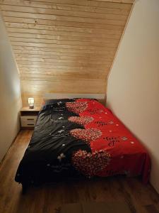 ein Schlafzimmer mit einem roten Bett mit einer Holzwand in der Unterkunft Vikendica L&V home in Valjevo