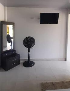 een zwarte ventilator in een witte kamer met een spiegel bij apartamento tranquilo rodeado de zonas verdes in Acacías