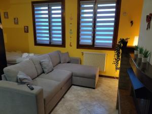 uma sala de estar com um sofá e duas janelas em Rifugio degli Dei em Monzuno