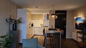 Zuiderzeestate 35, prachtig appartement aan het IJsselmeer في ماكوم: مطبخ وغرفة معيشة مع طاولة وكراسي