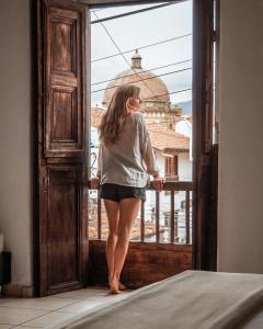 Una mujer parada en una puerta mirando por una ventana en THIS IS COLOMBIA HOSTEL, en San Gil