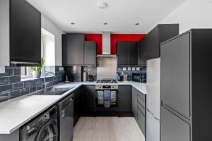 a kitchen with black and white cabinets and appliances at Stylish 2 Bed Bungalow in East Ham, Close to Excel in London