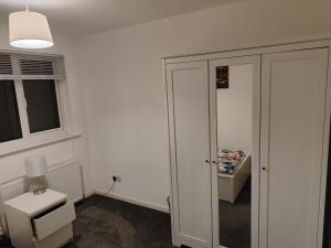 a room with a closet and a table and a lamp at Perfect Place in Walsall/ 4 bedroom / long term workers or family home in Walsall