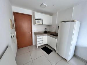 a kitchen with a white refrigerator and a brown door at 902. Flat Blend - Proibido fumar in Brasília