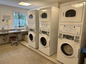 lavadero con 3 lavadoras y lavamanos en Lindo ap garden Soul Paulista 102, en São Paulo