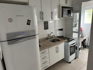 Una cocina blanca con fregadero y refrigerador. en Lindo ap garden Soul Paulista 102, en São Paulo