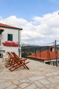 un patio con 2 sillas de madera y una sombrilla en Casa na Aldeia 1º Andar, en Arcos de Valdevez