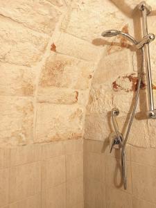 a shower in a bathroom with a stone wall at La Rosa dei Trulli B&B in Alberobello