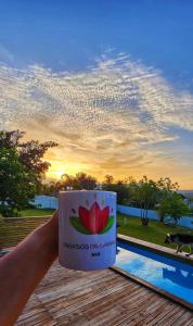 una persona sosteniendo una taza de café frente a una piscina en PARAISOS DE GABRIELA en Villalba