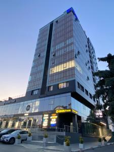 wysoki budynek z samochodem zaparkowanym przed nim w obiekcie Large and Cozy Apartment in the Center w Kiszyniowie