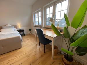 ein Schlafzimmer mit einem Schreibtisch, einem Bett und einer Pflanze in der Unterkunft Stadtoase: Exklusive Apartments für Ruhe und Entspannung in Bremen