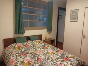 Appartement centre في آير سور لادور: غرفة نوم بسرير ولحاف ورد ونافذة