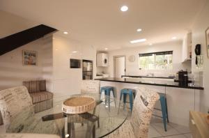 cocina con mesa de cristal y sillas en Raintrees Moffat Beach en Caloundra