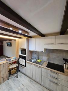 uma cozinha com armários brancos e uma cadeira em MAISON BONHEUR em Villaret