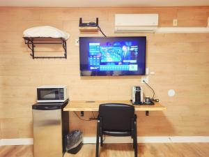 um quarto com uma secretária e uma televisão na parede em Harbour Light Motel em Nanaimo