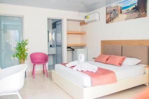 1 dormitorio con 1 cama y 1 silla rosa en HOTEL PIEDRA VIVA en Capurganá