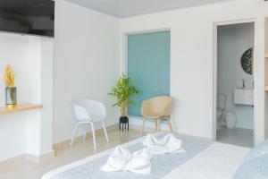 HOTEL PIEDRA VIVA في كابورغانا: غرفة نوم ذات أثاث أبيض وكراسي بيضاء